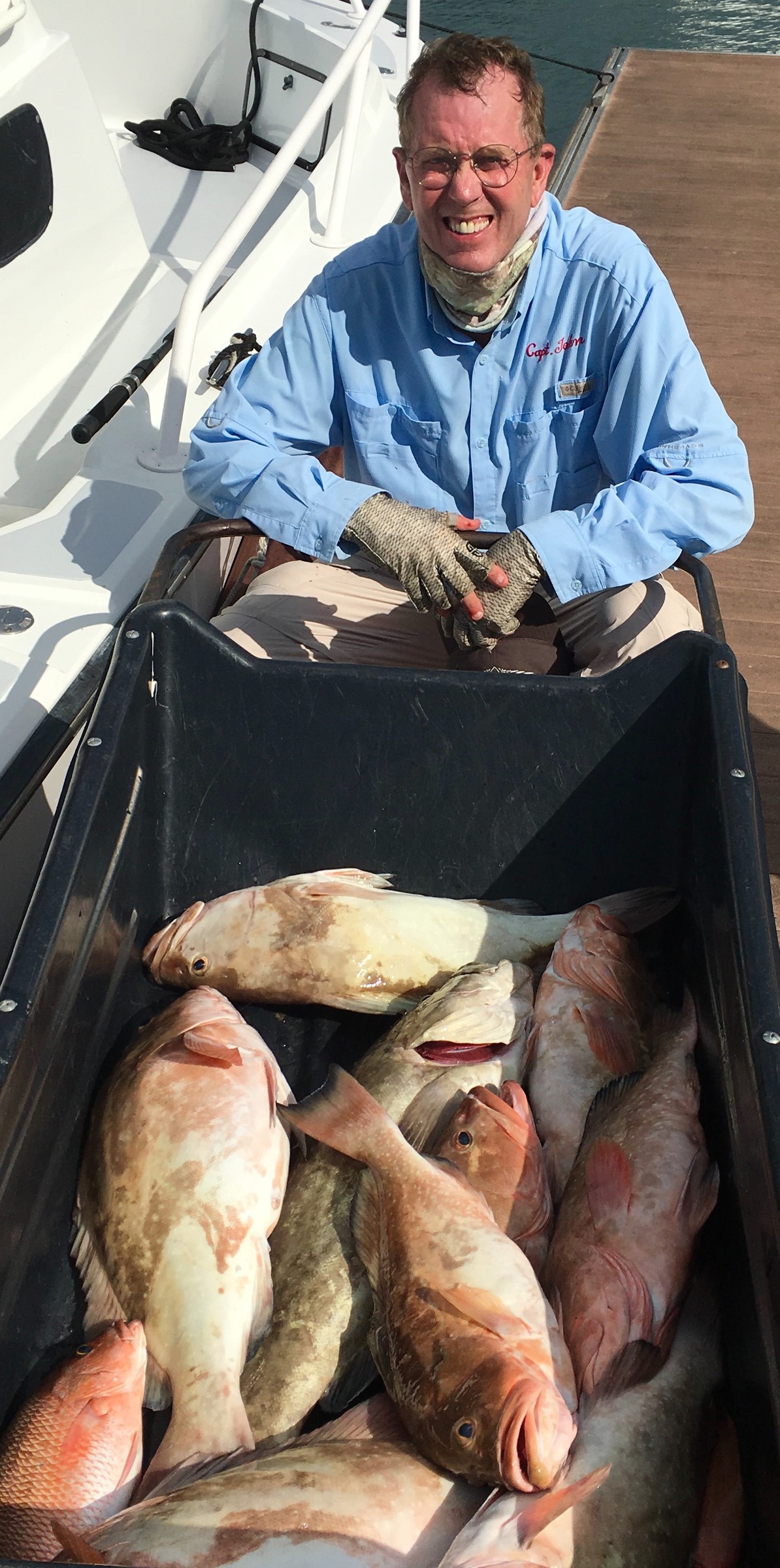An angler beside a cooler filled with fish