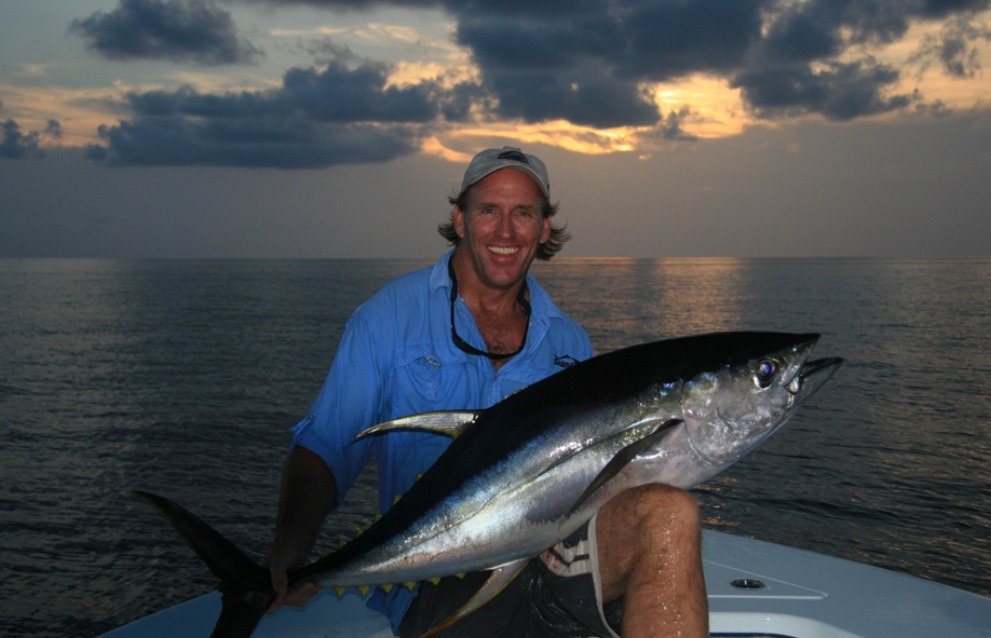 An angler displaying a tuna at sunset