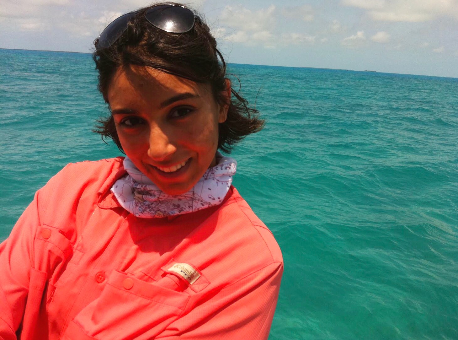 An angler in a coral shirt beside turquoise water
