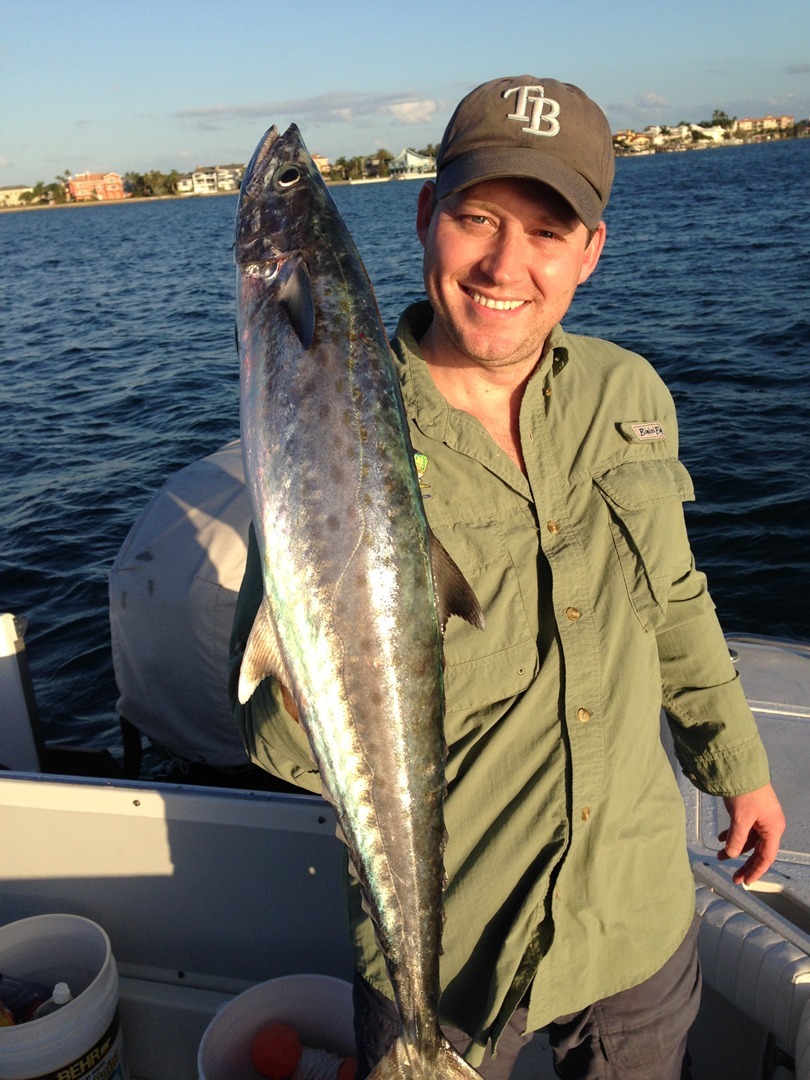 An angler in an olive shirt raising his catch
