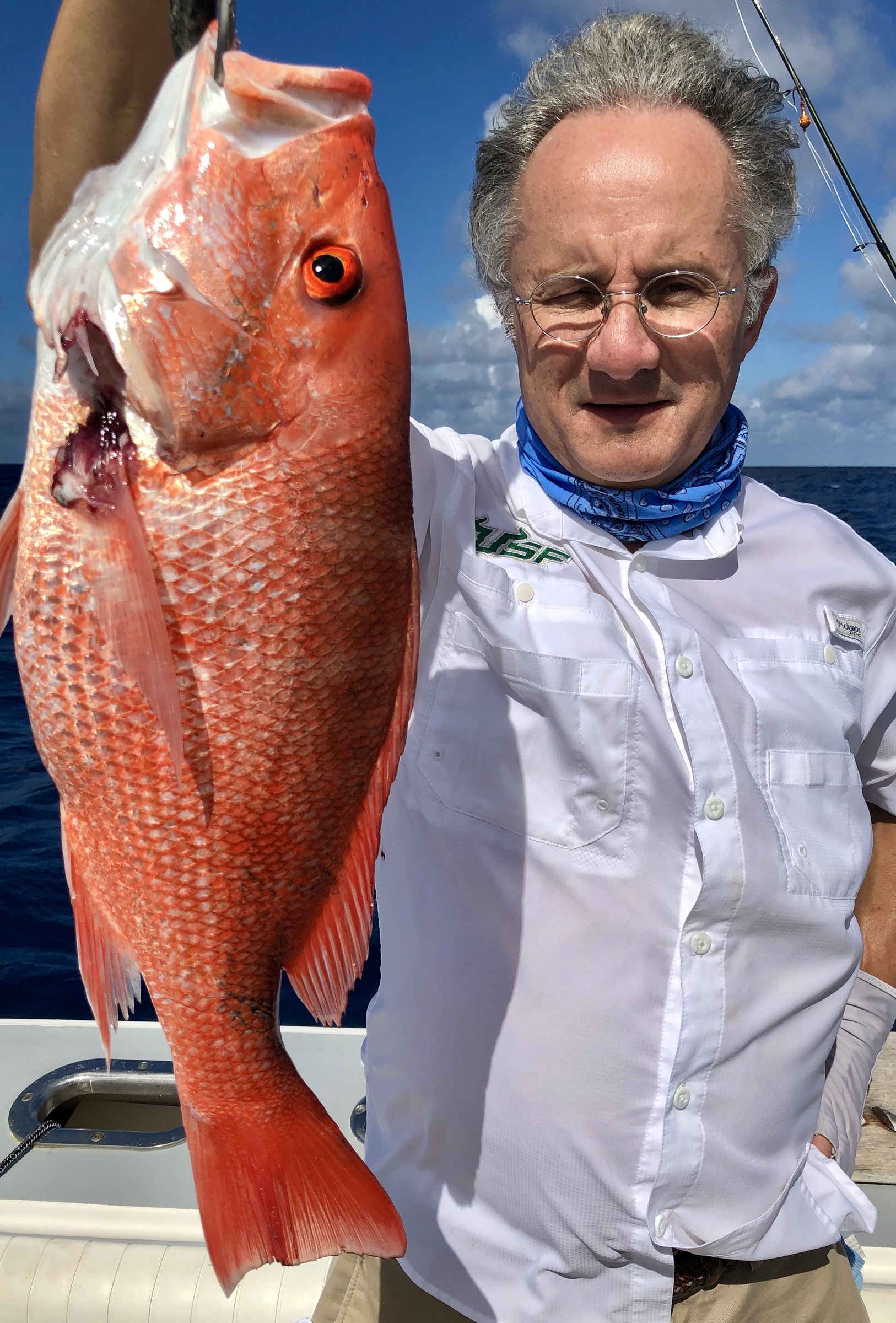 An angler holding a red fish beside the cabin